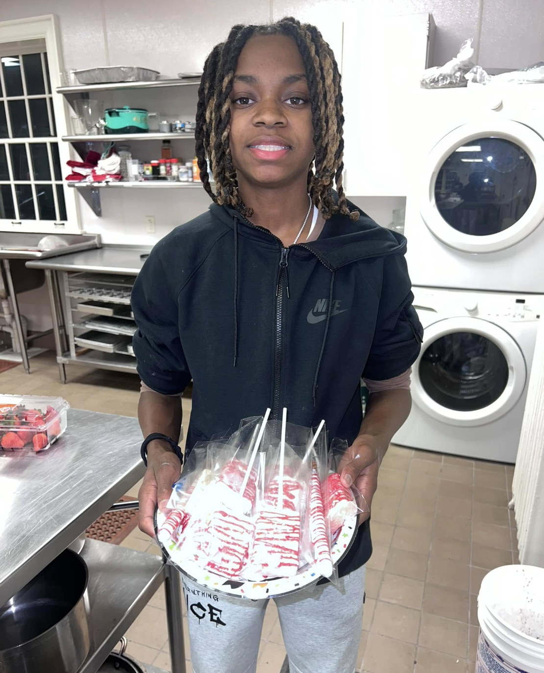 Baker glazing a tray of donuts with pastel icing