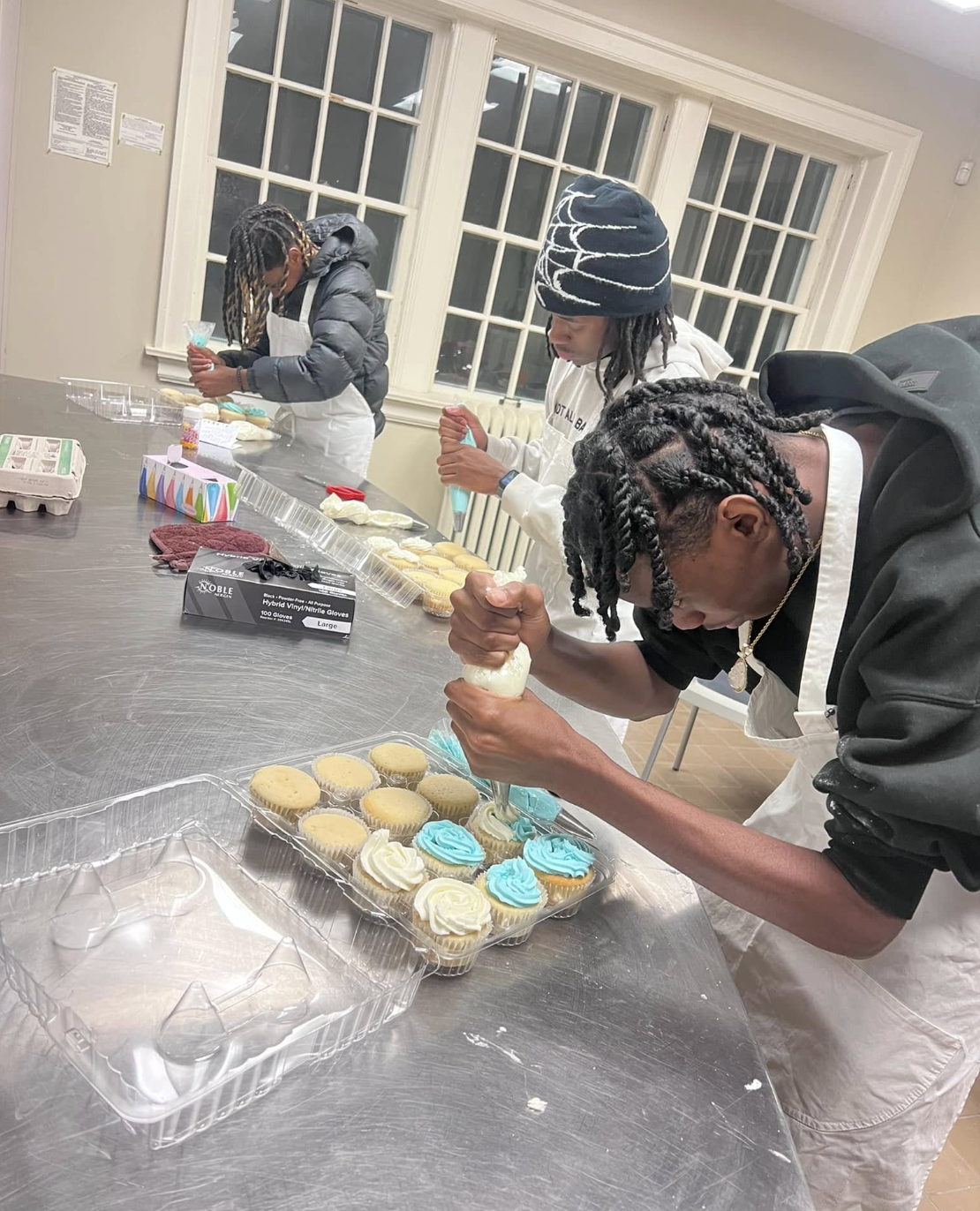 Baker carefully piping buttercream swirls onto cupcakes